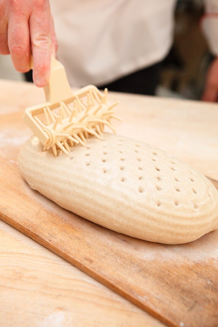 Bread dough being perforated with a pin roller