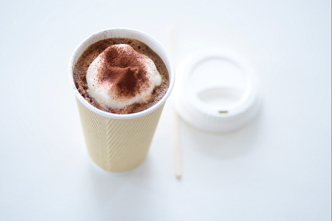 A mug of cocoa with cream in a take away cup
