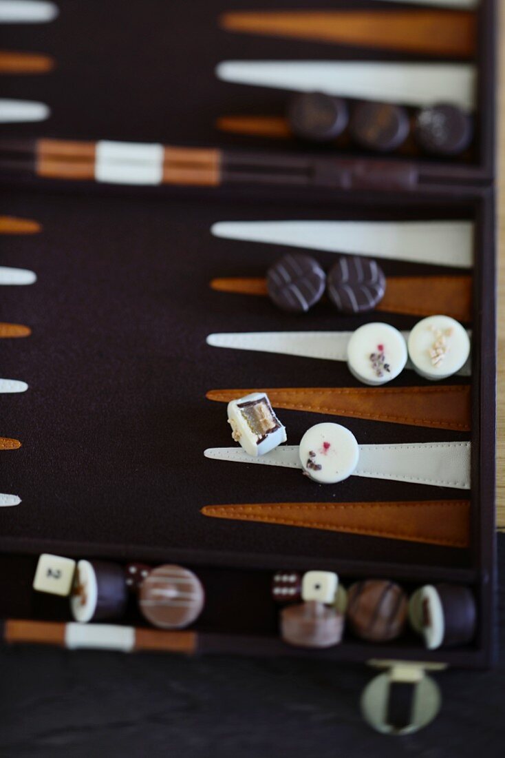 Verschiedene Pralinen auf einem Backgammon-Brett