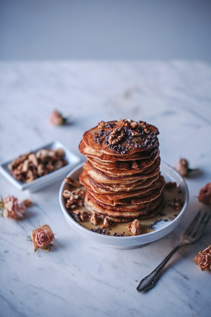 Ein Stapel Pancakes mit Ahornsirup, Walnüssen und Kakaonibs