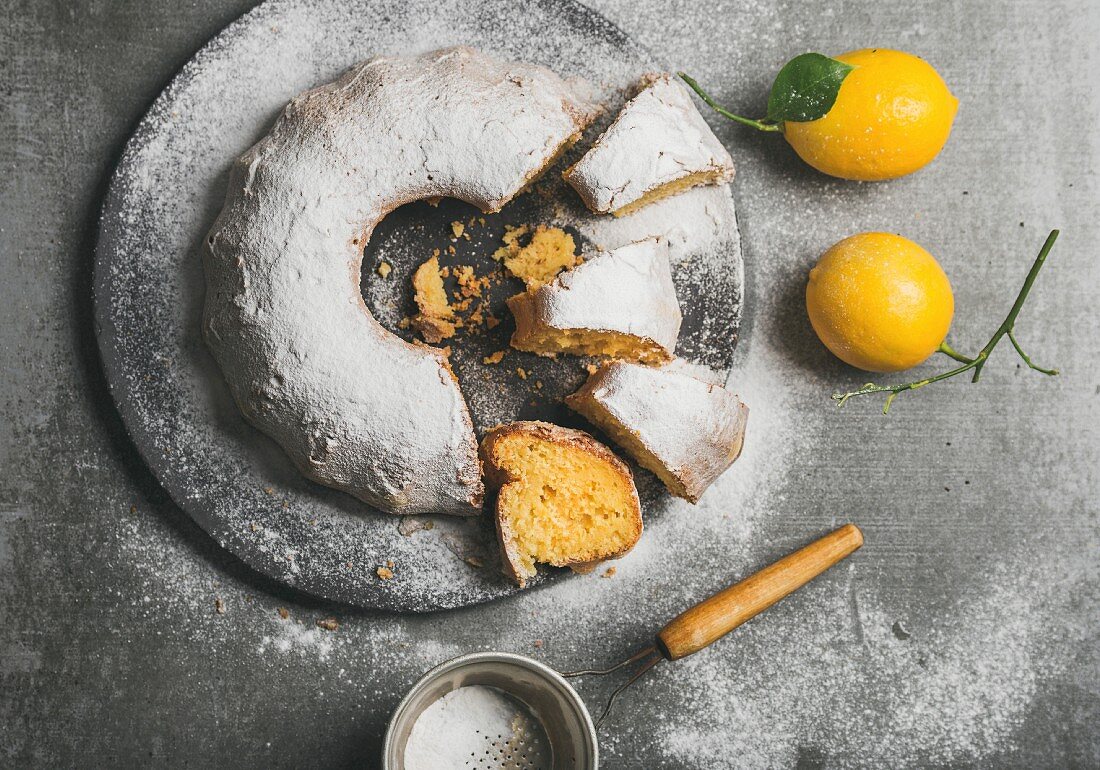 Glutenfreier Zitronen-Kranzkuchen mit Puderzucker, angeschnitten (Aufsicht)