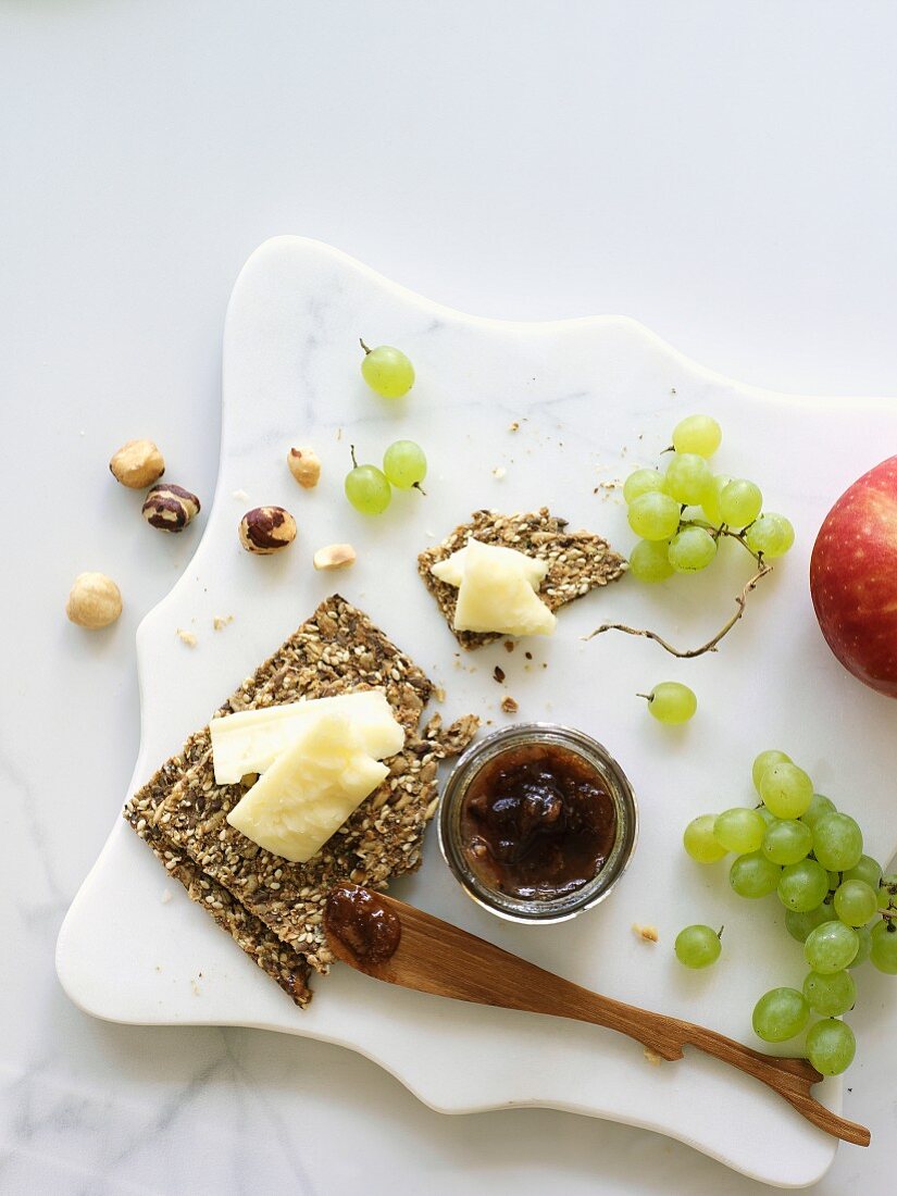 White Cheddar cheese block with crackers, grapes and jam