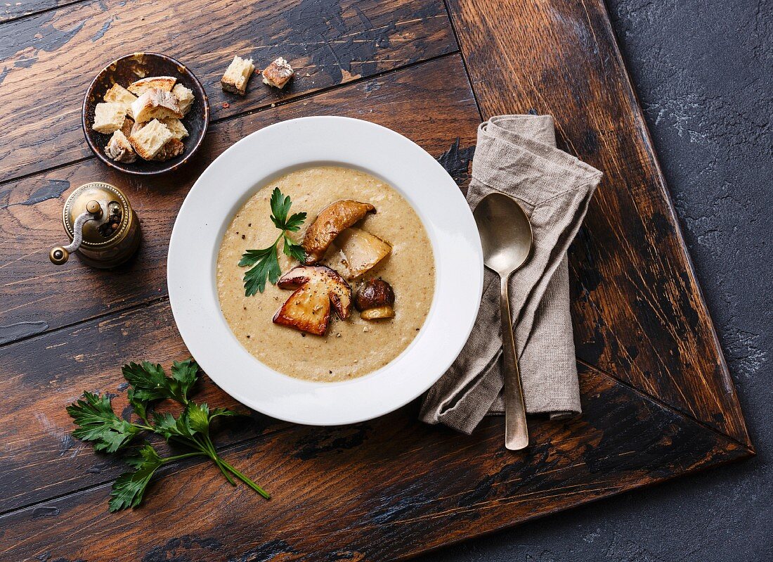 Cream-soup with porcini mushroom with croutons on wooden table