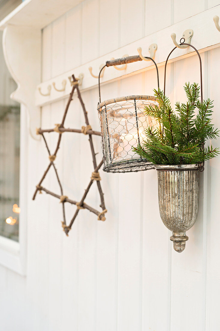 Star made from twigs, candle lantern and conifer sprigs hung from pegs