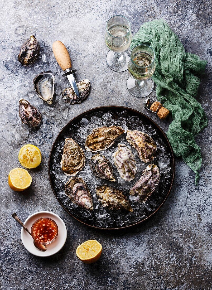 Oysters in plate with spicy sauce and champagne on stone texture background