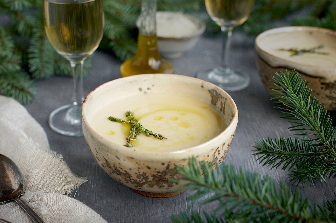 Asiago White Bean Soup with Thyme Oil served in ceramic bowls with white wine on a gray background