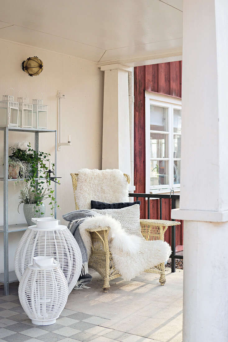 Rattansessel mit Schaffellen und Laternen auf der Veranda