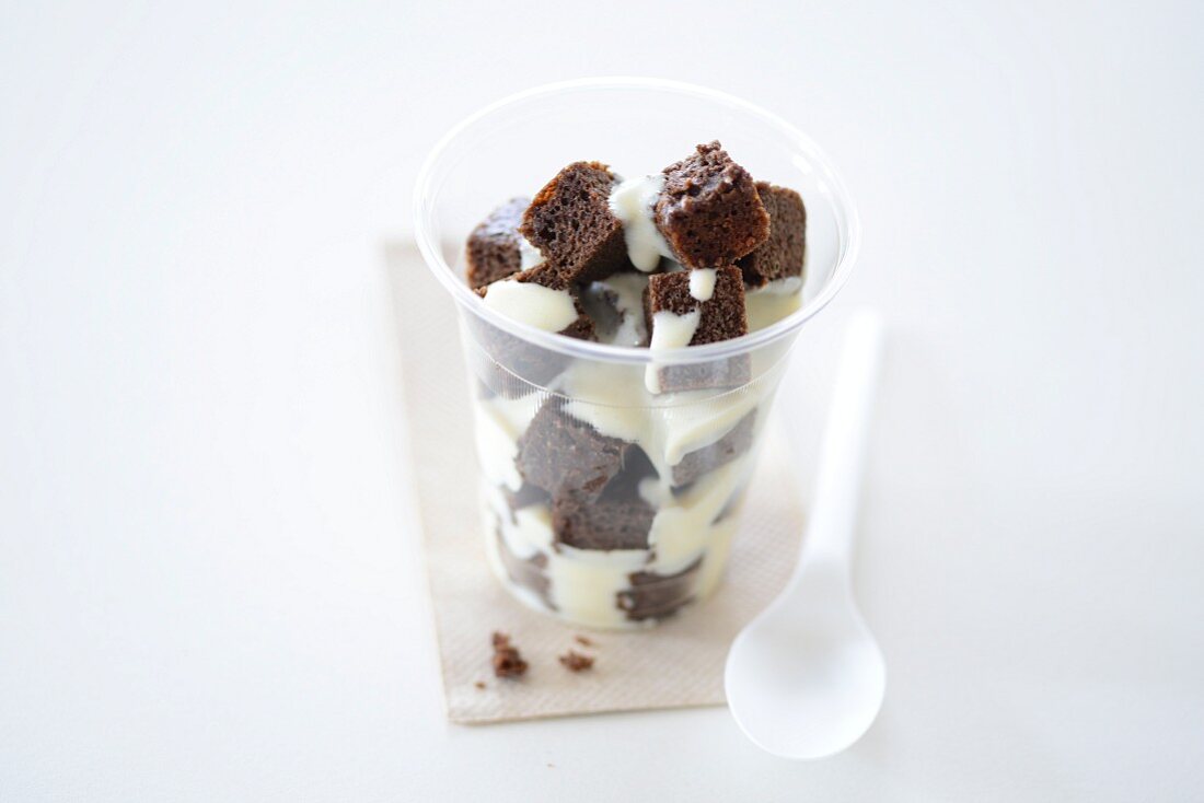 Brownies with vanilla sauce in a takeaway cup