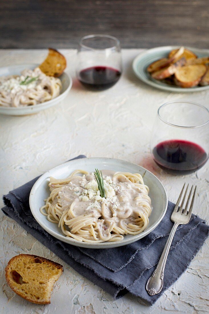 Spaghetti mit Gorgonzola-Rosmarinpesto serviert mit Brot und Wein