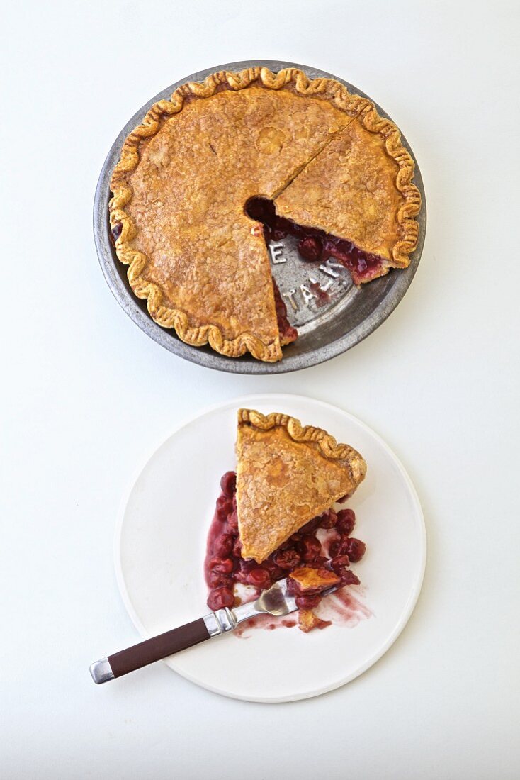 Sauerkirschpie, angeschnitten in der Form und Kuchenstück auf Teller