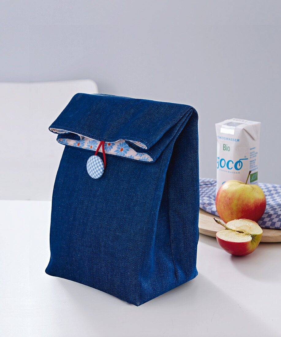A denim lunch bag with button fastening