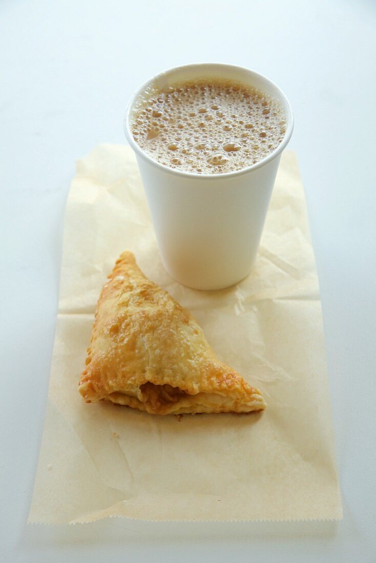Coffee in a paper cup and apple turnover on a napkin