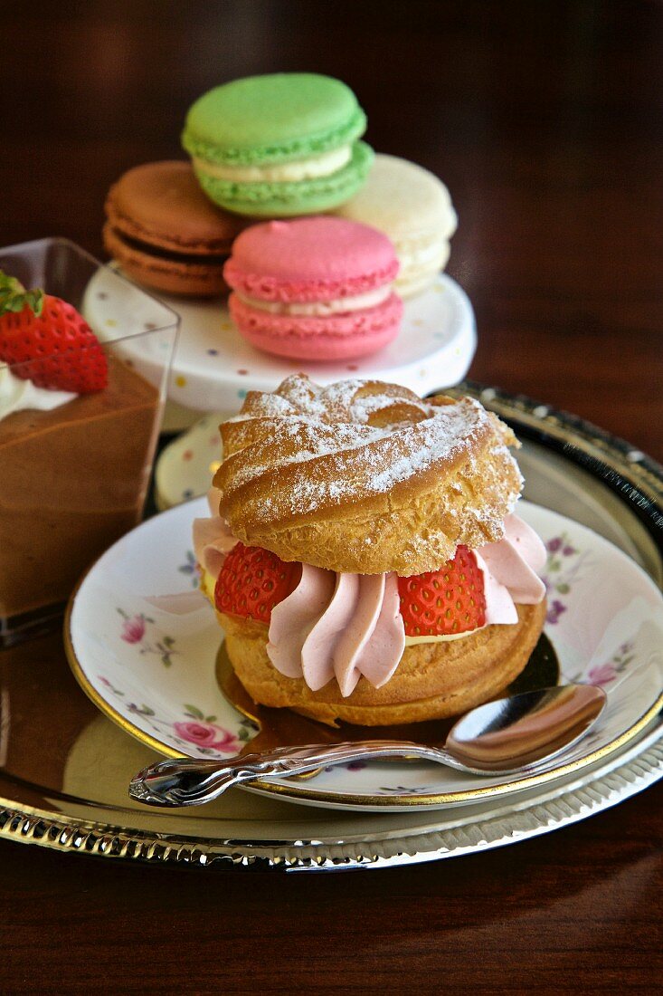 Windbeutel mit Erdbeersahne, Macarons und Schokoladendessert auf Silbertablett