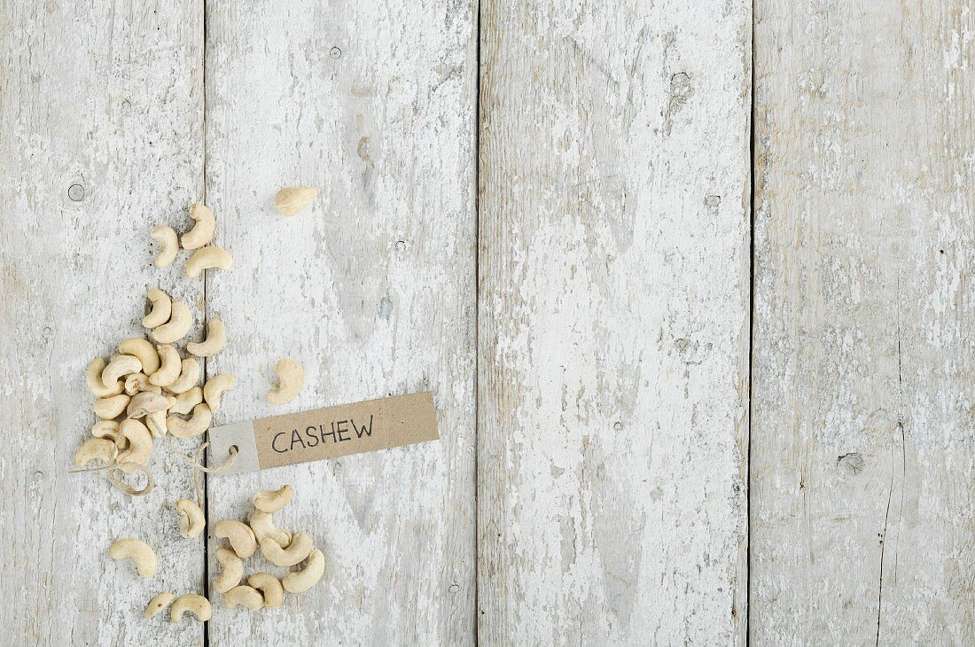 Cashew nuts with a brown paper label on a wooden background (top view)