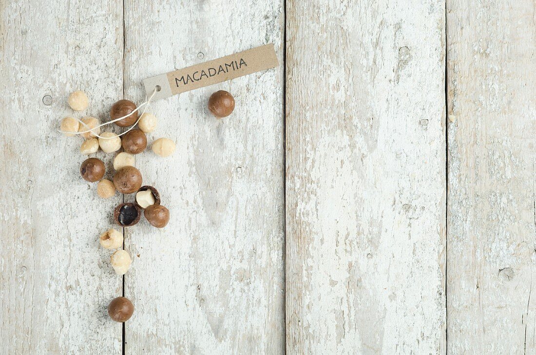 Macadamia nuts with a brown paper label on a wooden background (top view)