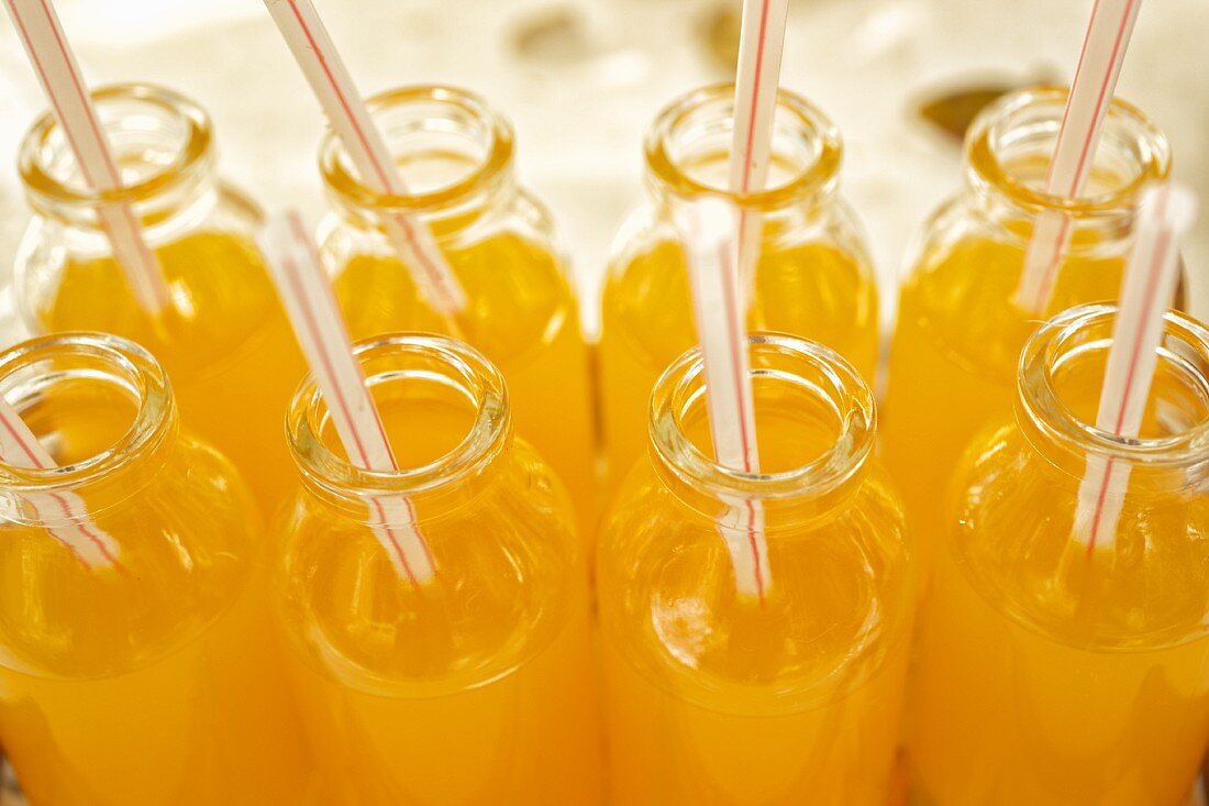 Orangensaft-Flaschen mit Strohhalmen