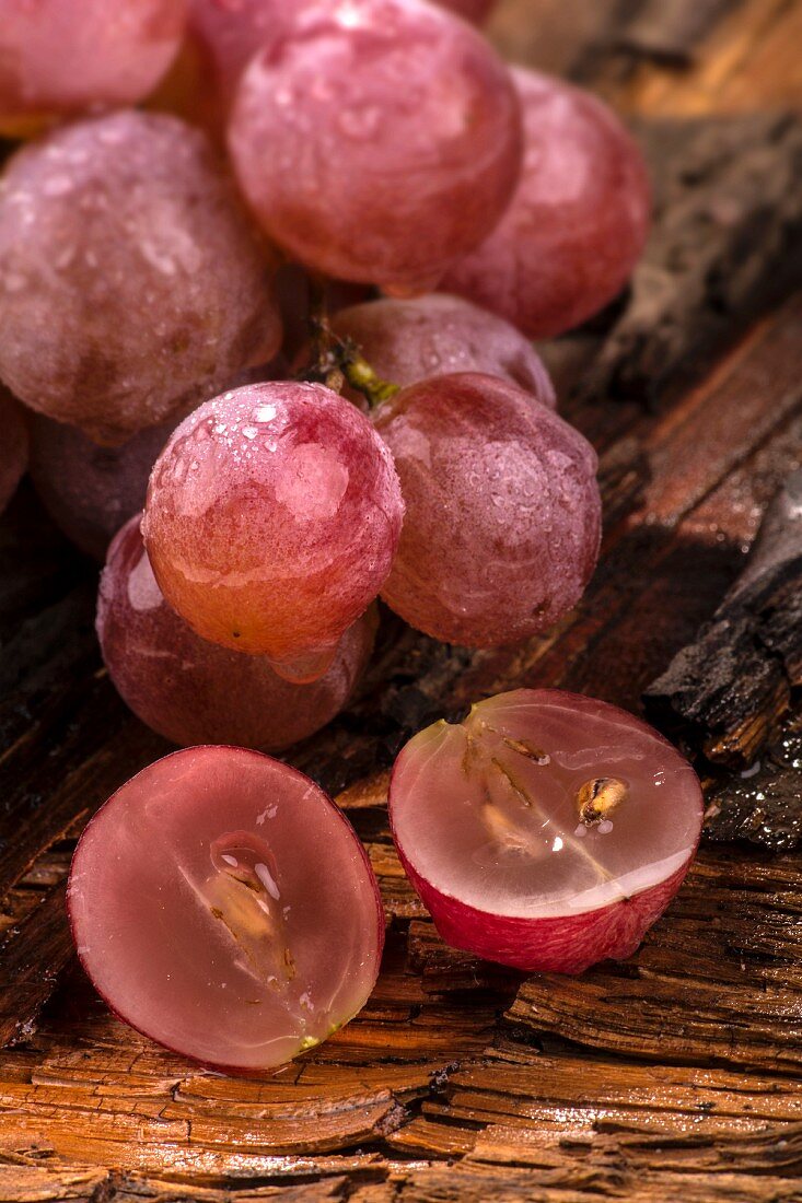 Red grapes with water droplets, one halved