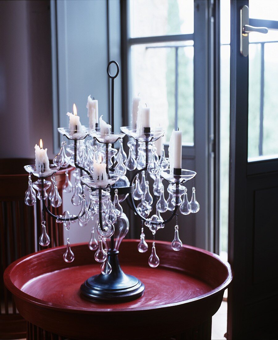 Candlelit candelabra on red tray in front of open French window