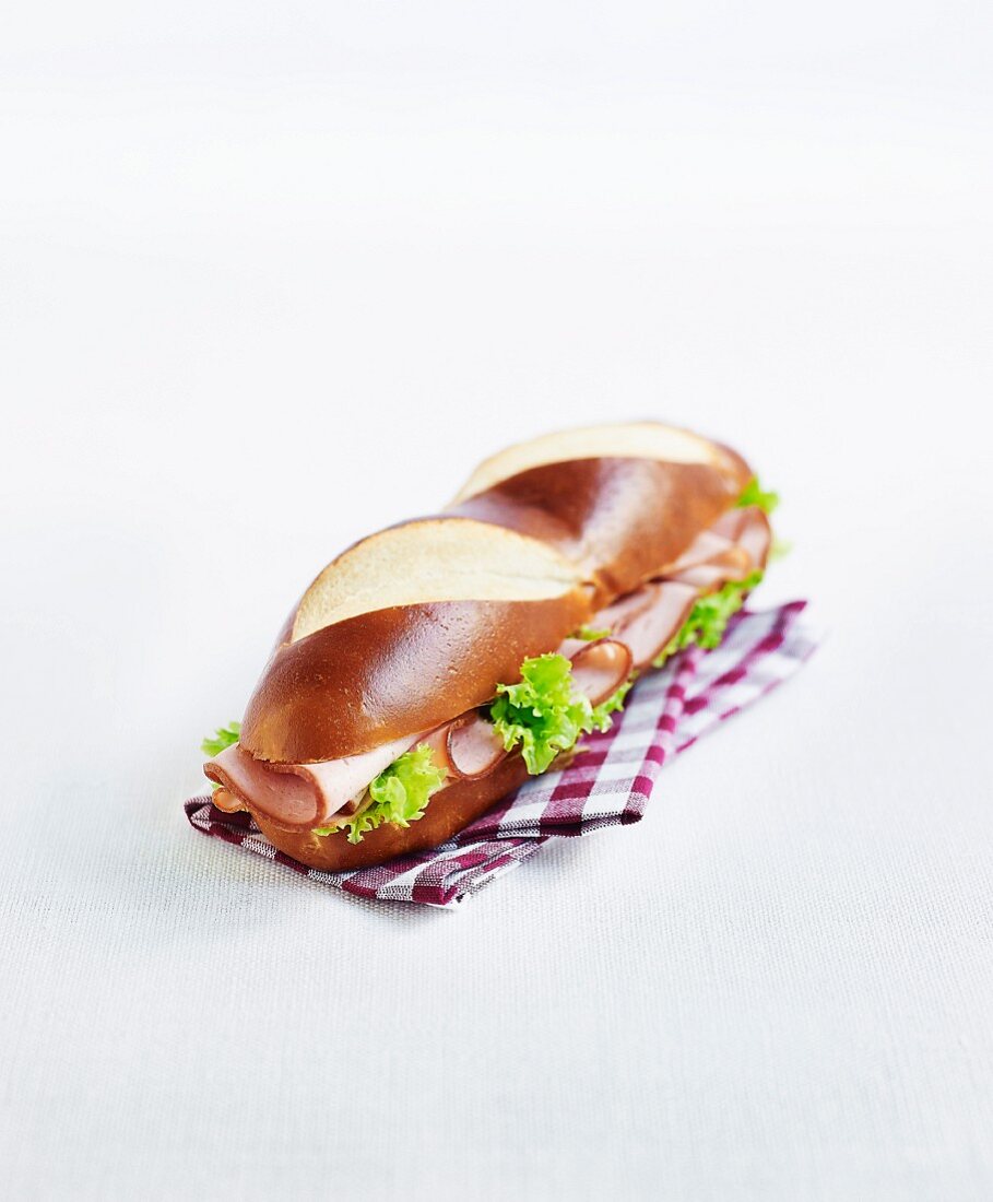 A lye bread sandwich with ham and lettuce