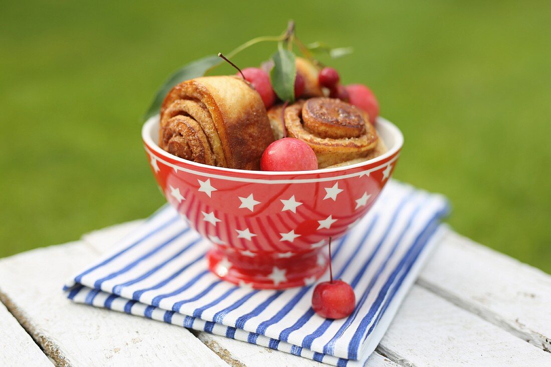 Zimtschnecken in roter Schale mit Zwergäpfeln