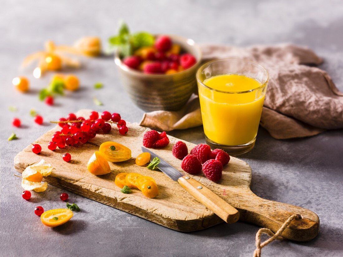 Frisches Obst auf Schneidebrett und ein Glas Fruchtsaft