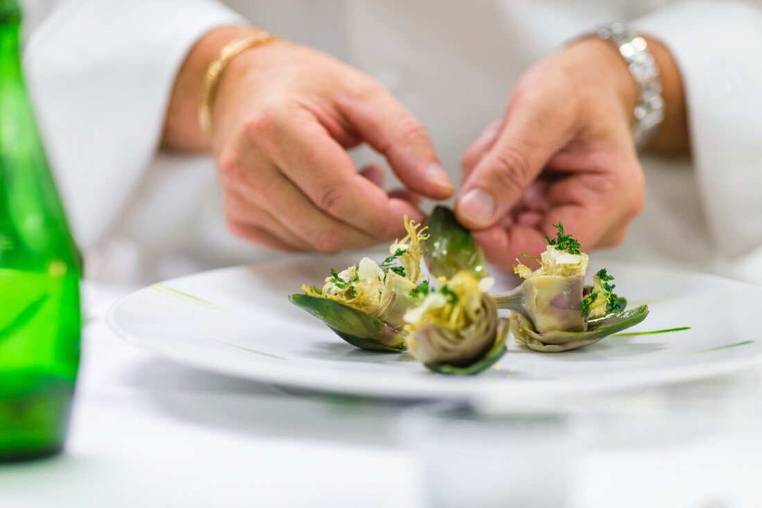 A chef arranges marinated artichokes on a plate