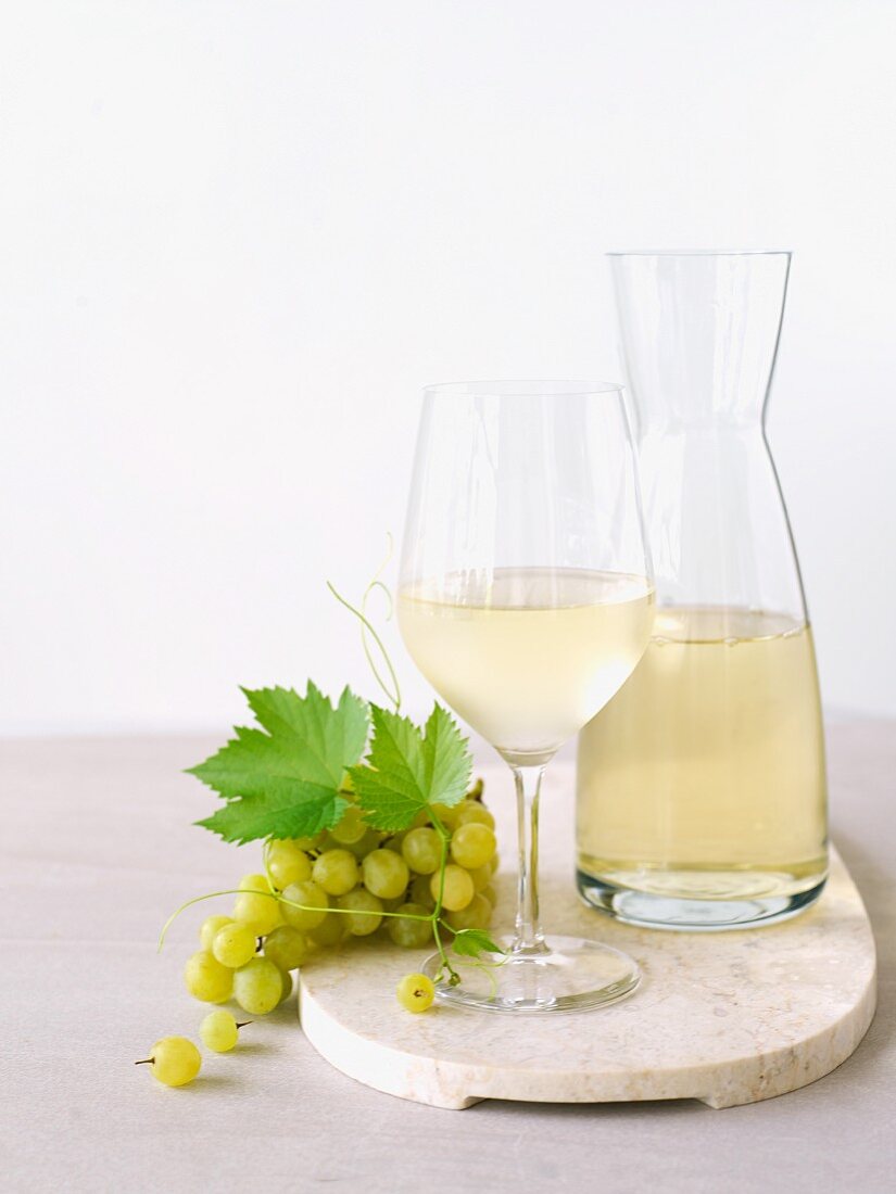 Weißwein in Glas und Karaffe, grüne Trauben