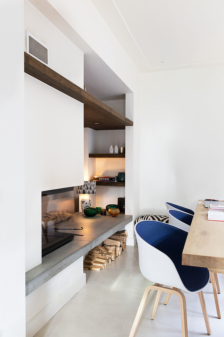 Modern shell chairs with blue seats in front of fireplace with shelves