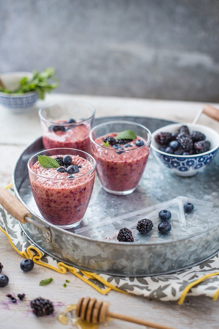 Beeren-Smoothies in Gläsern mit Honig und frischen Beeren