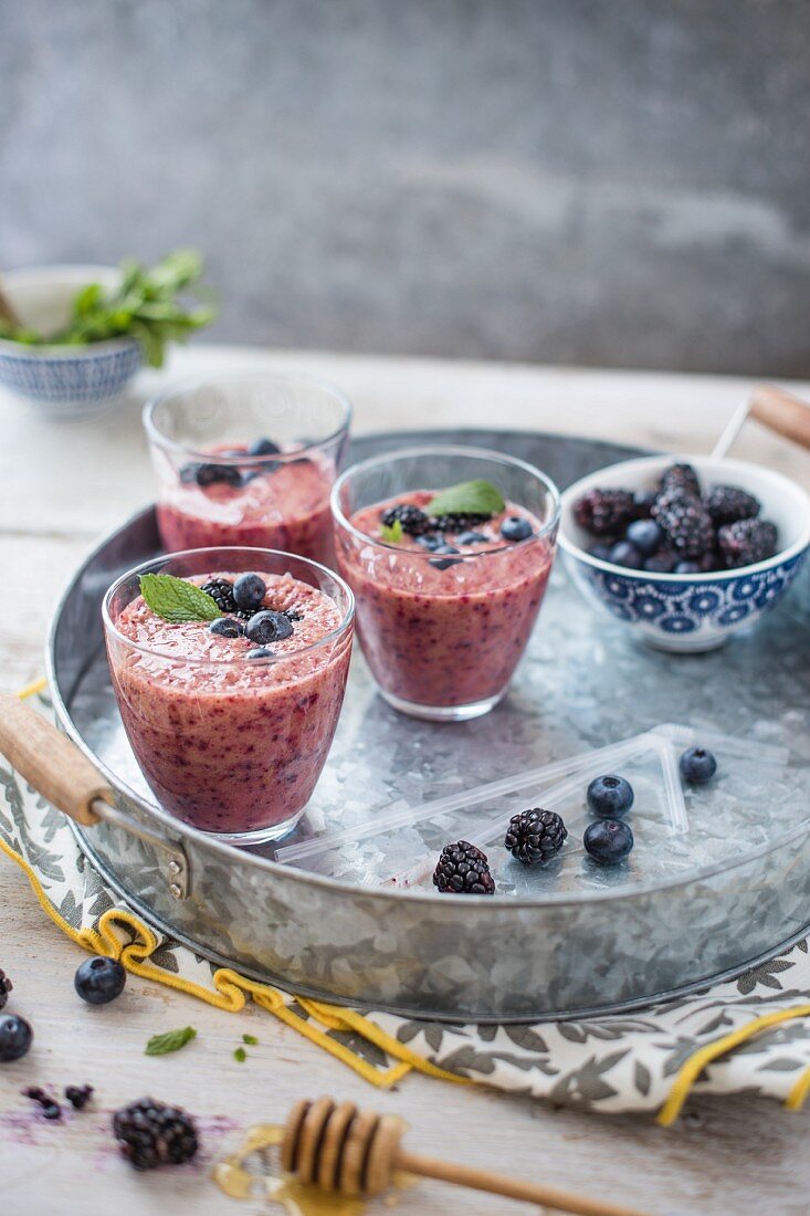 Berry smoothie in glasses with honey and berries