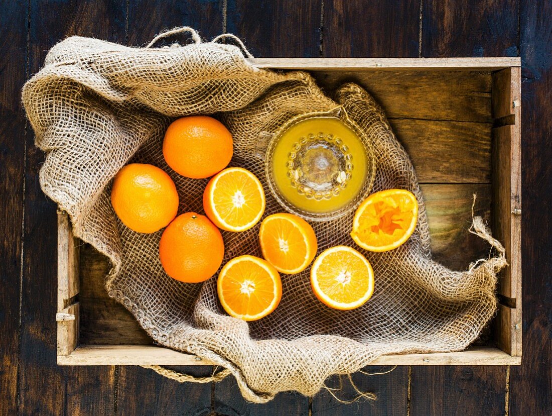 Box of fresh oranges - some squeezed to make fresh orange juice