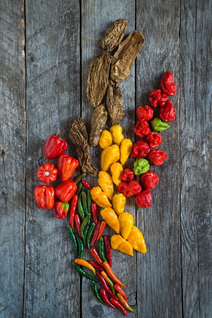 Various chilli peppers on a wooden background