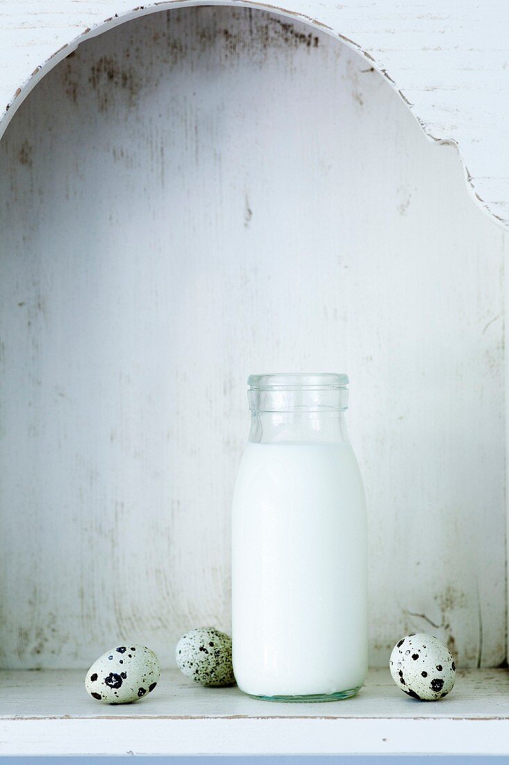 Milch in Flasche zwischen Wachteleiern