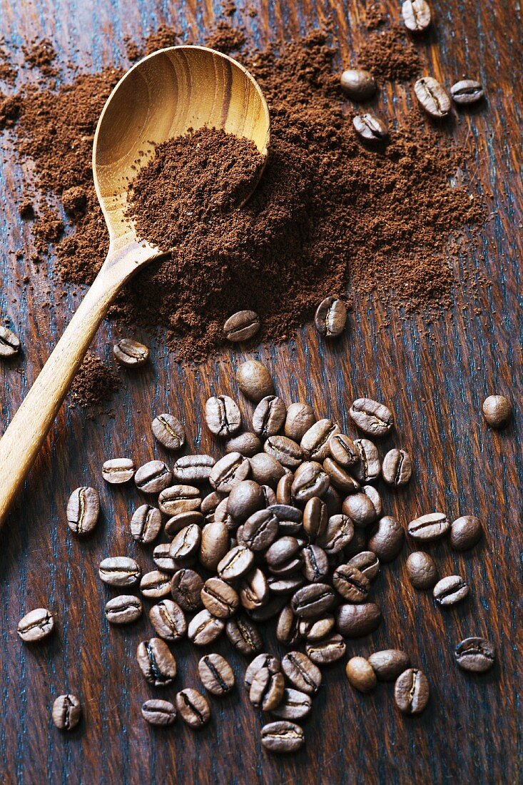 Coffee beans and ground coffee with a wooden spoon