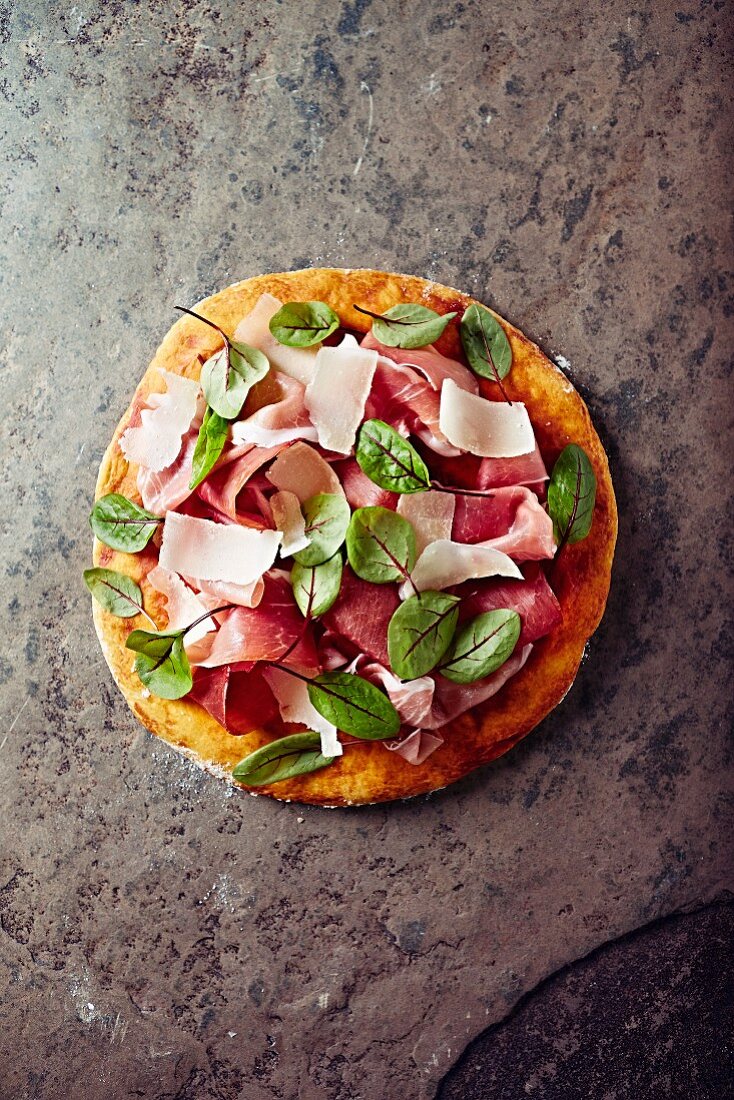 Pizza topped with cured ham, parmesan and red sorrel