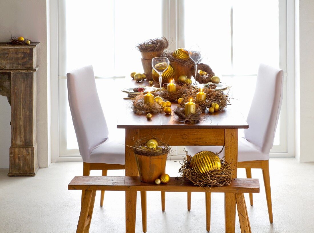 Small wreaths of wild flowers festively arranged on table with gold baubles and candles