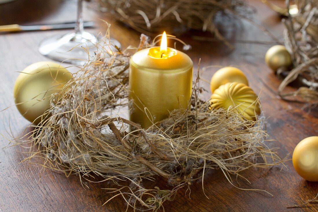 Gold candle in dried wreath on wooden table decorated with Christmas baubles
