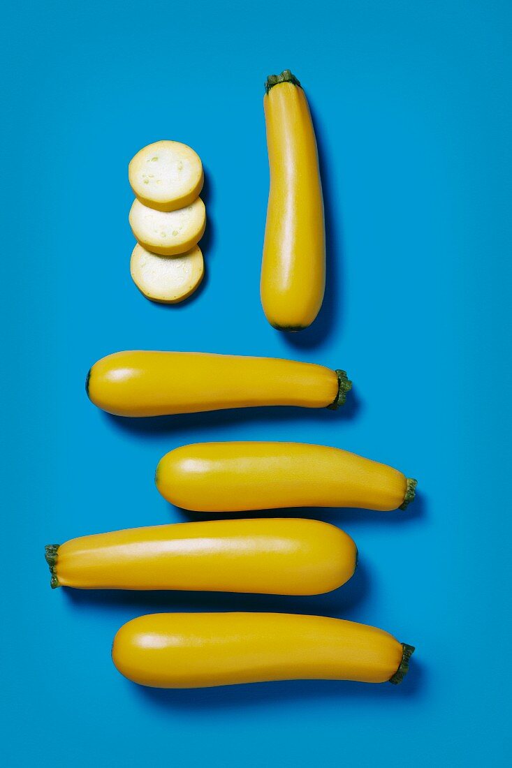 Several yellow zucchinis, whole and sliced