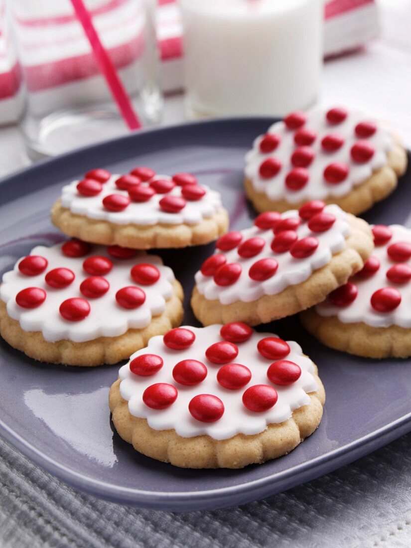 Cookies verziert mit weißem Zuckerguss und roten Schokolinsen