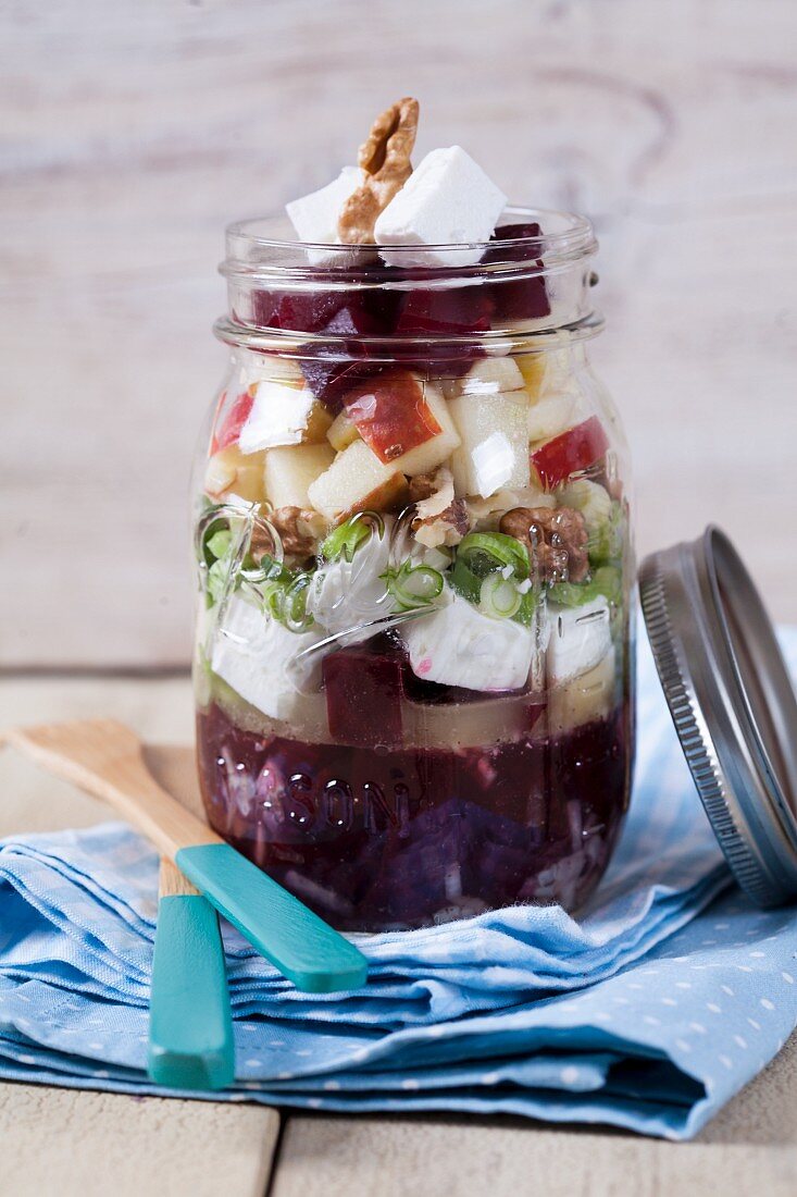 Beetroot with goat's cheese, apple, walnuts, olives and onions in a glass jar