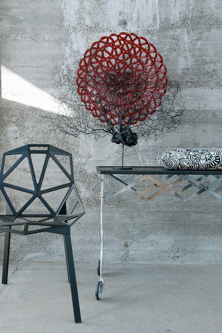 Black sea fan coral and red glass dish on designer table next to black metal chair