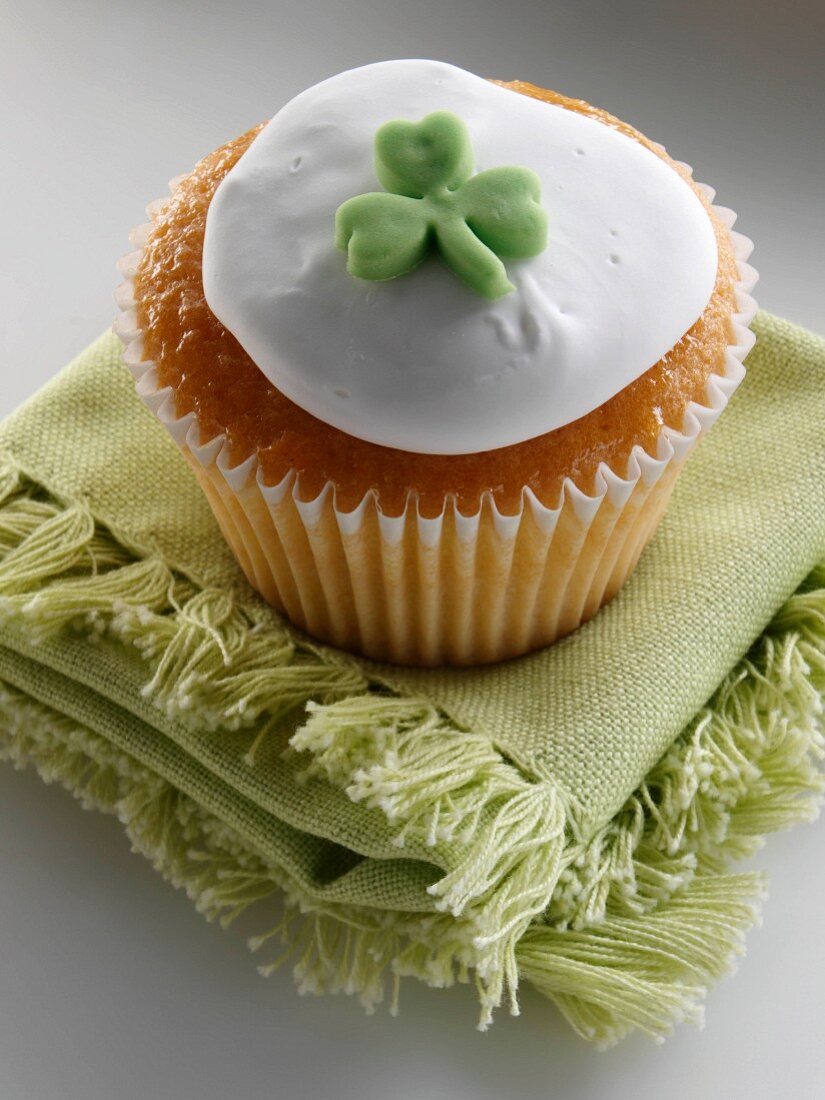 Cupcake dekoriert mit Zuckerglasur und grünem Fondant-Kleeblatt (Nahaufnahme)