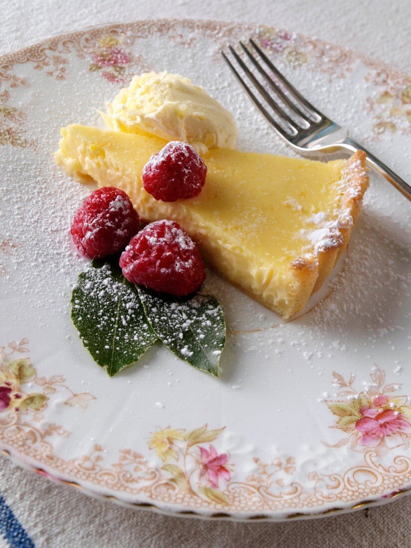 Ein Stück Lemon Tarte (Zitronenkuchen) mit Himbeeren auf Teller