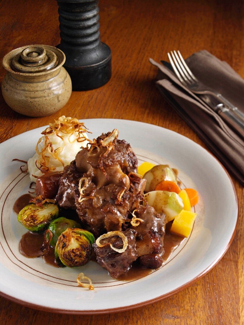 Oxtail casserole with turnips carrots Brussels sprouts caramelized onions mashed potato and gravy