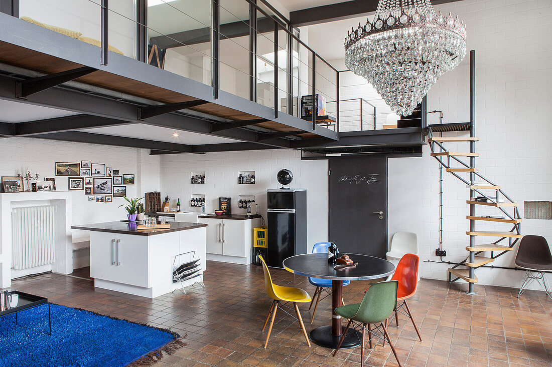 Offene Küche und runder Esstisch mit Designerstühlen im Industrie-Loft