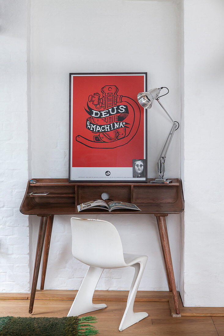 White designer chair at wooden desk with red artwork