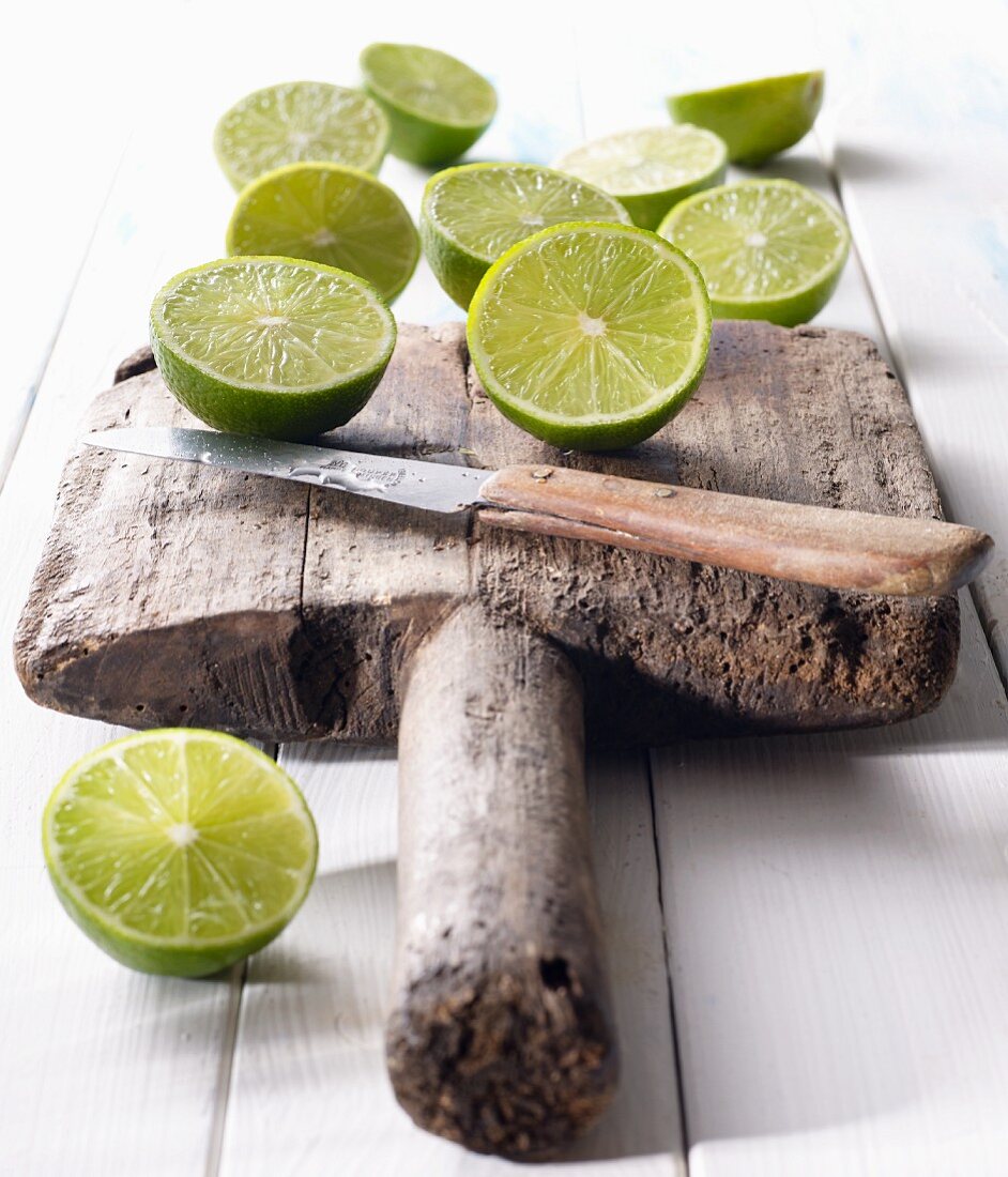 Halved limes on an old wooden board with a knife