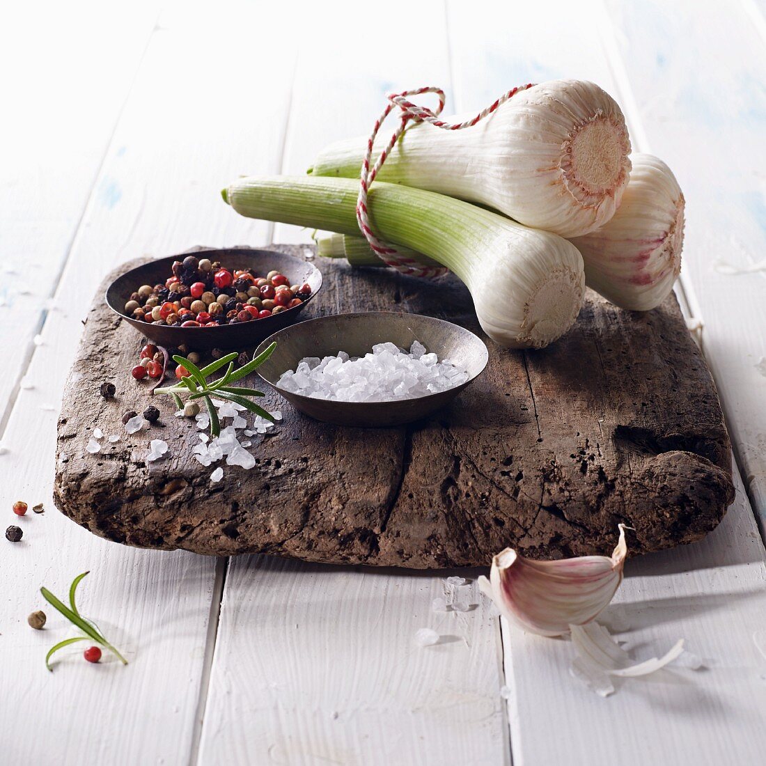 Fresh bulbs of garlic with salt and colourful pepper on a wooden board