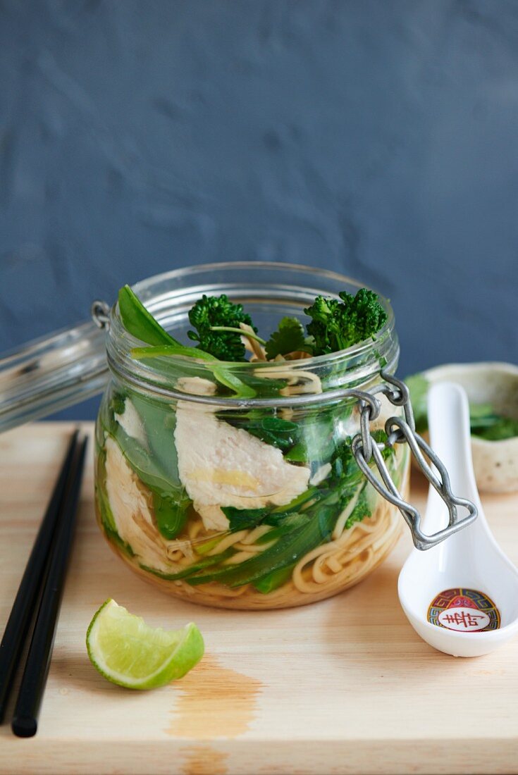 Noodles with chicken, sugar snaps and broccoli in a glass jar (Asia)