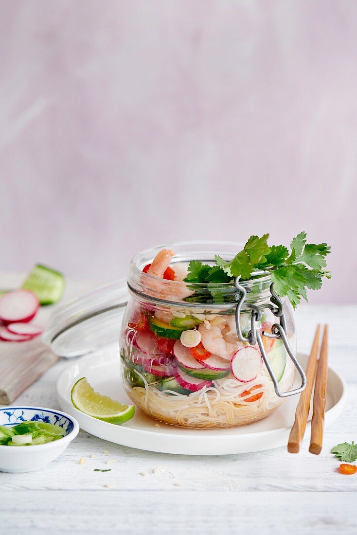A noodle salad with radishes and shrimps in a glass jar